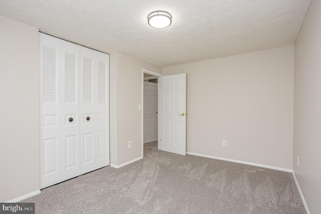 unfurnished bedroom featuring carpet, a textured ceiling, and a closet