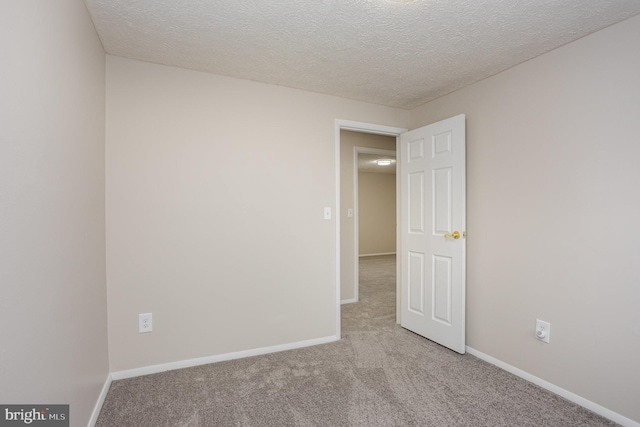 spare room featuring light colored carpet and a textured ceiling