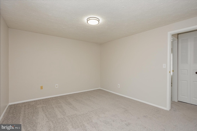 empty room with light colored carpet and a textured ceiling