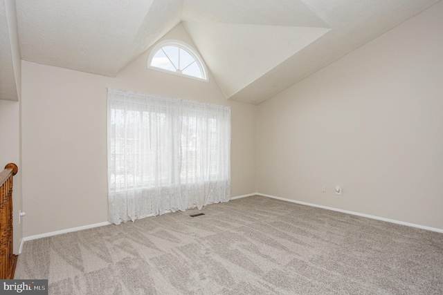 spare room featuring light carpet, lofted ceiling, and a textured ceiling