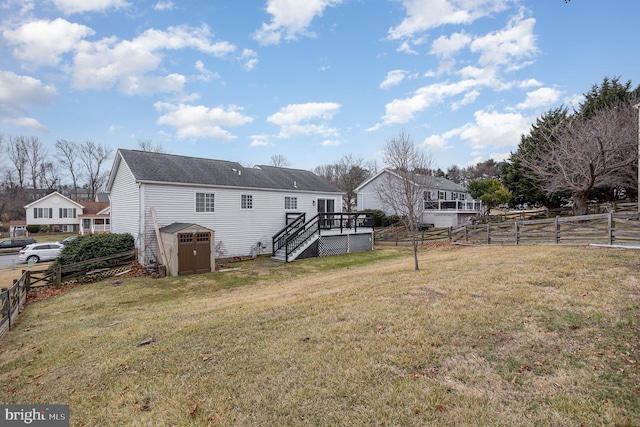 back of house with a yard, a deck, and a shed