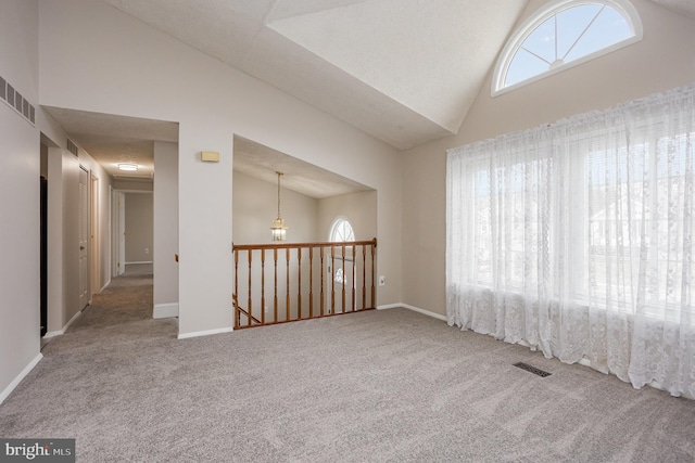 carpeted empty room with high vaulted ceiling