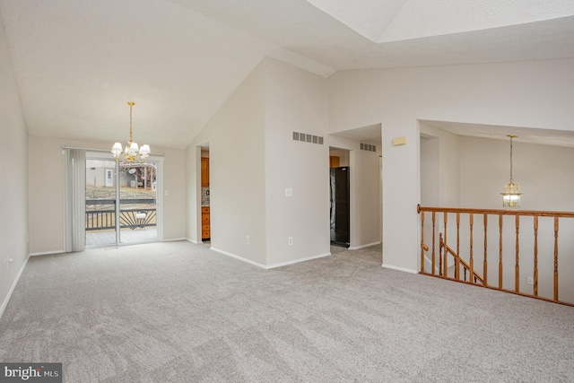 carpeted spare room featuring high vaulted ceiling and an inviting chandelier