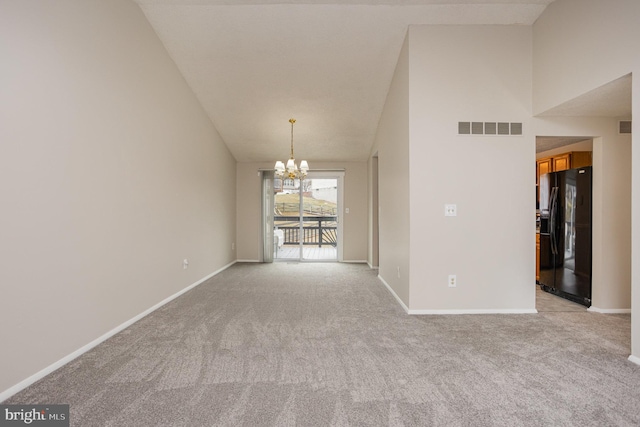 carpeted spare room with an inviting chandelier and a high ceiling