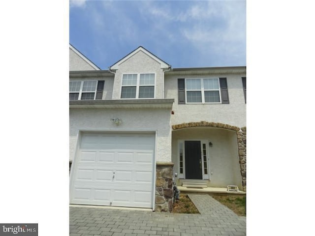 view of front of home with a garage, decorative driveway, and stucco siding