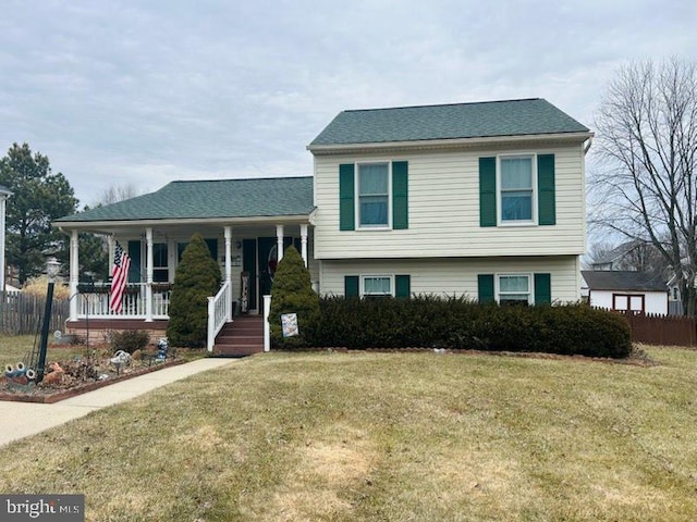 tri-level home with a porch, a front yard, and fence