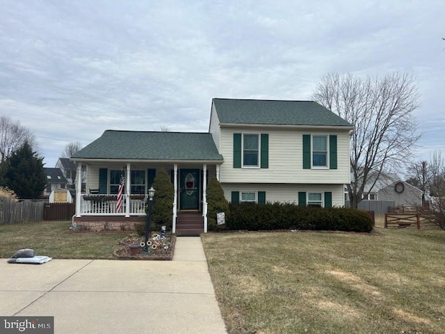 tri-level home featuring a porch, a front lawn, and fence