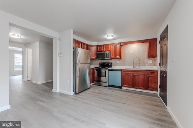 kitchen with sink, decorative backsplash, light hardwood / wood-style flooring, and appliances with stainless steel finishes