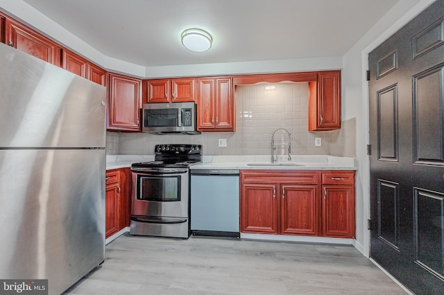 kitchen with sink, decorative backsplash, light hardwood / wood-style flooring, and stainless steel appliances