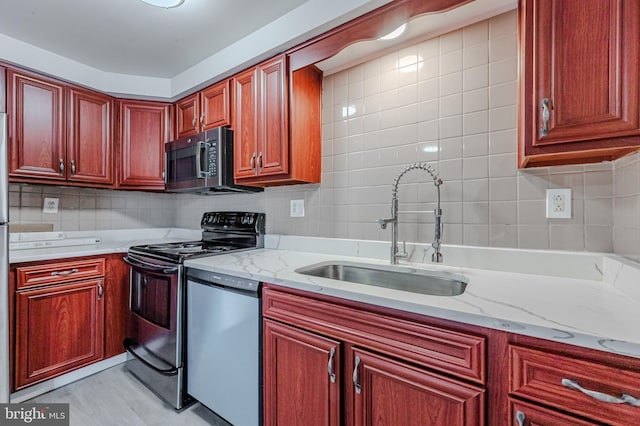 kitchen featuring light stone counters, stainless steel appliances, sink, and backsplash