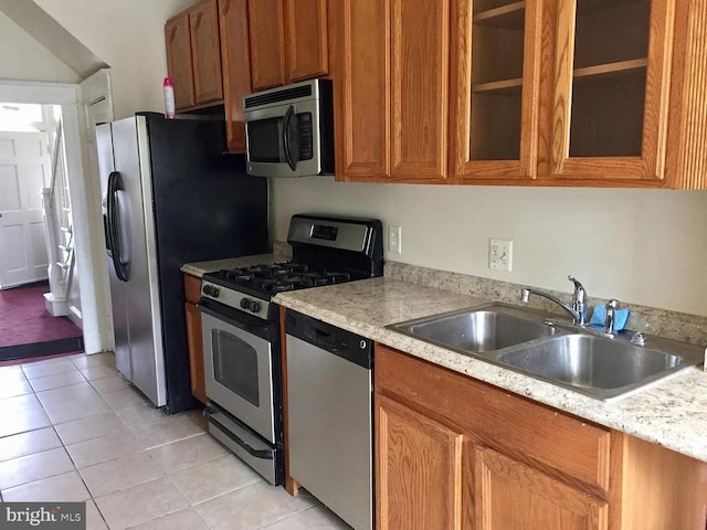 kitchen with stainless steel appliances, sink, light tile patterned floors, and light stone counters