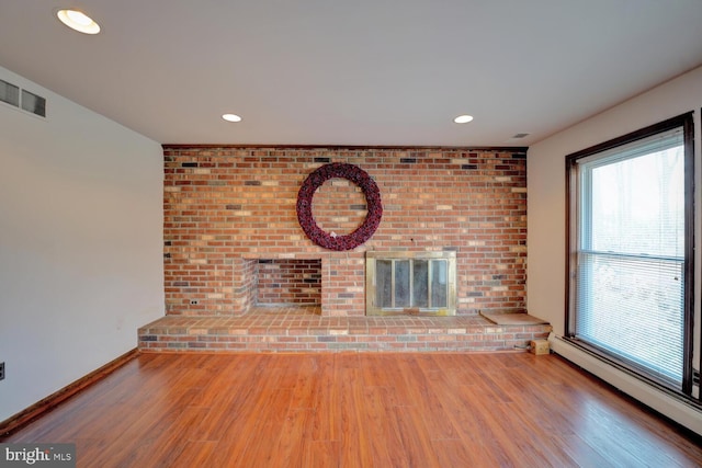 338 Blue Heron Rd, Dover, DE 19904 - unfurnished living room featuring brick wall, wood-type flooring, a brick fireplace, and a baseboard heating unit