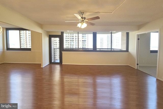 spare room with wood finished floors, a wealth of natural light, and baseboards