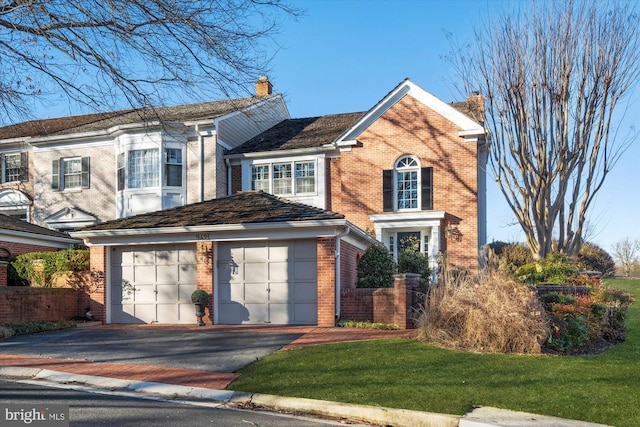 traditional-style home with driveway, an attached garage, a chimney, and brick siding