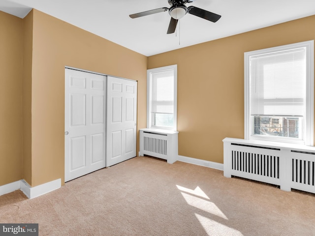 unfurnished bedroom with radiator, light colored carpet, and a closet