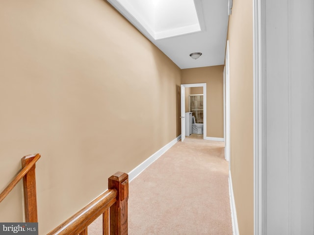 hall with a skylight and light colored carpet