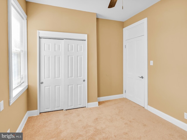 unfurnished bedroom with light carpet, ceiling fan, and a closet