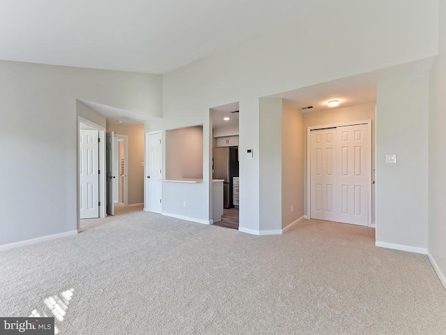 empty room featuring light carpet and high vaulted ceiling