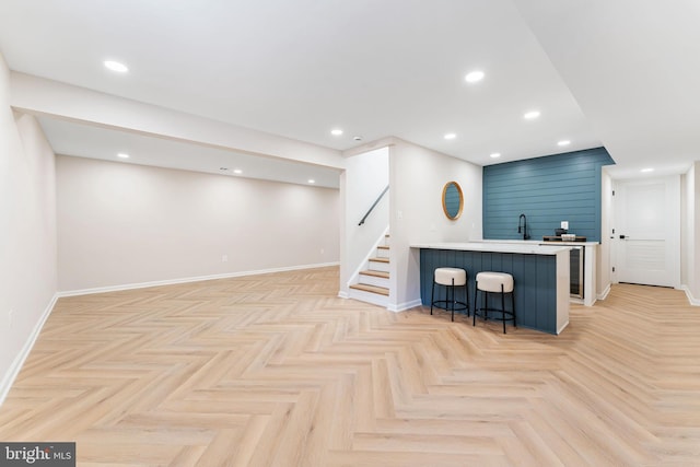 kitchen featuring recessed lighting, a kitchen breakfast bar, light countertops, and a sink