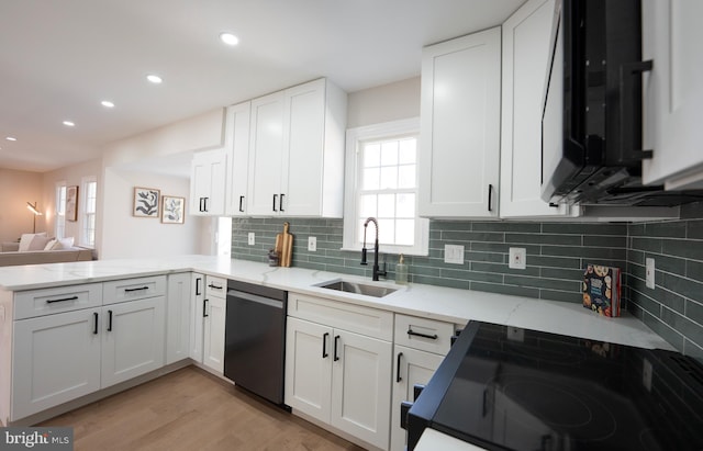 kitchen with a sink, light stone counters, white cabinetry, a peninsula, and dishwashing machine