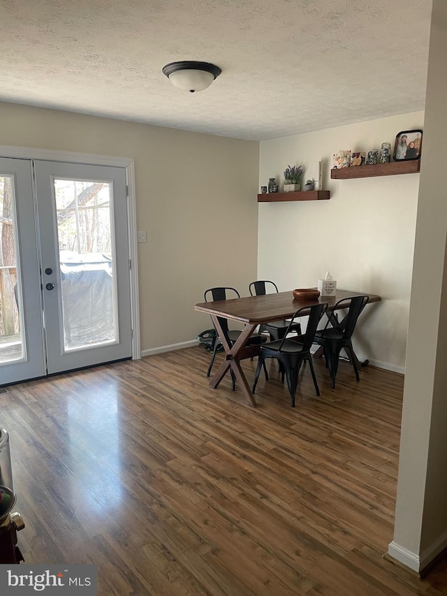 dining space featuring dark hardwood / wood-style floors, a textured ceiling, and french doors