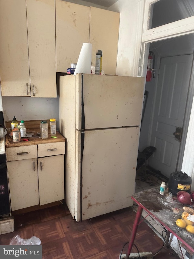 kitchen featuring dark parquet flooring, butcher block countertops, and white fridge