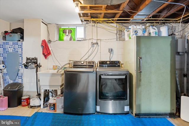 clothes washing area featuring washing machine and dryer, laundry area, and a sink