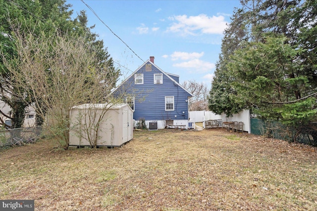 back of house featuring a storage shed, a yard, fence, and an outdoor structure