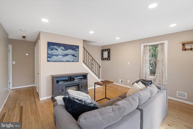 living area with baseboards, visible vents, stairway, light wood-style floors, and recessed lighting