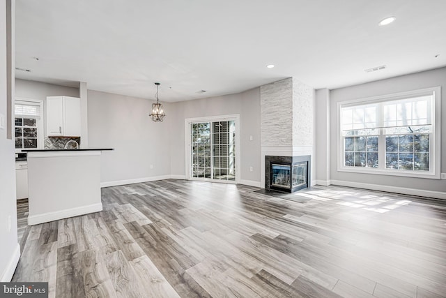 unfurnished living room with a fireplace, light wood-type flooring, and a healthy amount of sunlight