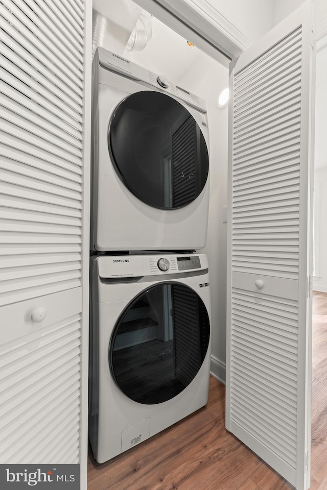 laundry room featuring hardwood / wood-style flooring and stacked washer and clothes dryer