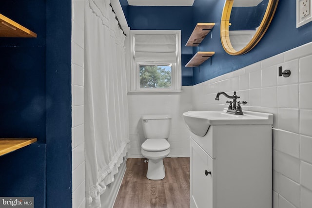 bathroom featuring vanity, toilet, hardwood / wood-style floors, and tile walls