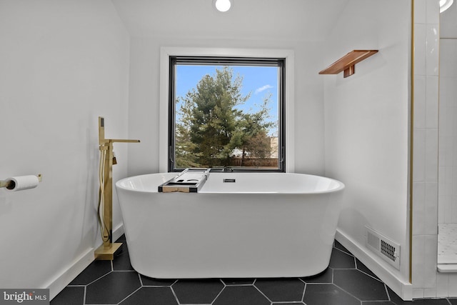 bathroom with a bath and tile patterned flooring