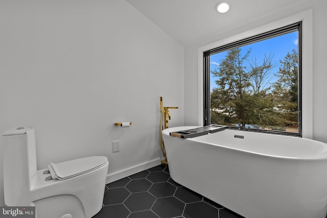 bathroom with vaulted ceiling, toilet, a bathing tub, and tile patterned flooring