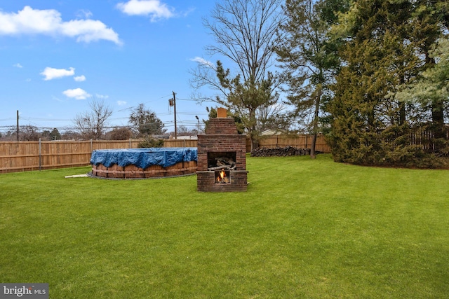 view of yard with an outdoor brick fireplace and a covered pool