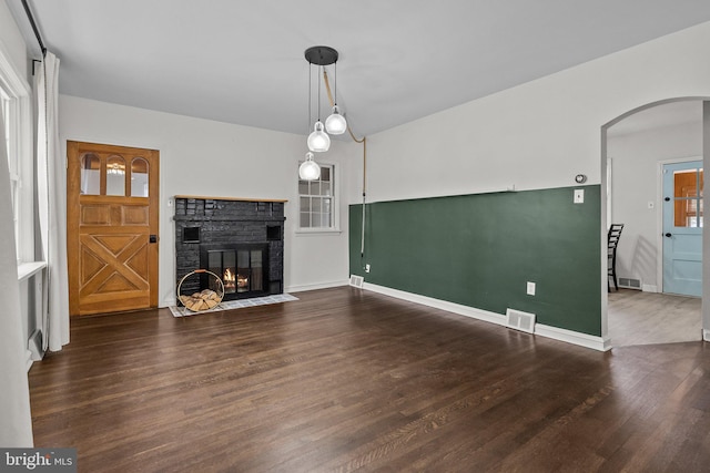 unfurnished living room with dark hardwood / wood-style flooring and a brick fireplace