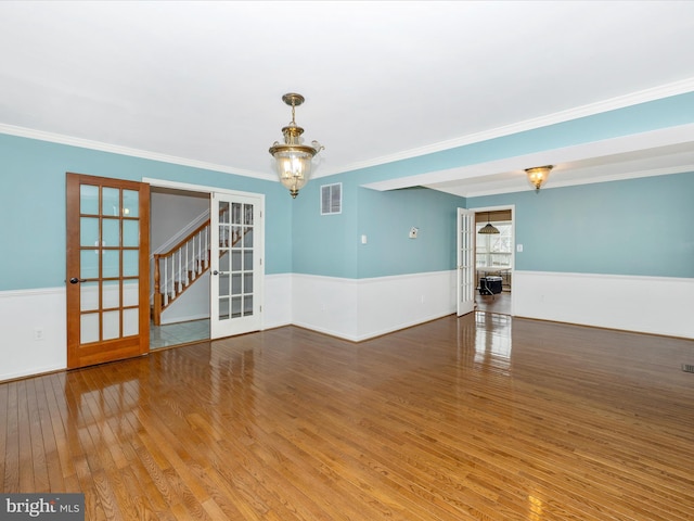 unfurnished room with an inviting chandelier, hardwood / wood-style flooring, crown molding, and french doors