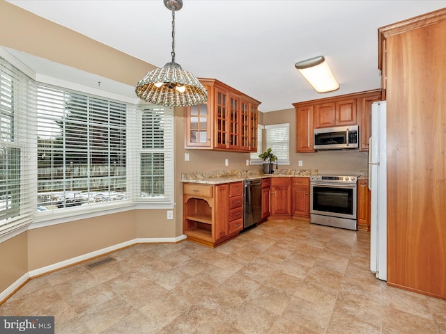 kitchen with pendant lighting, sink, light stone counters, and stainless steel appliances