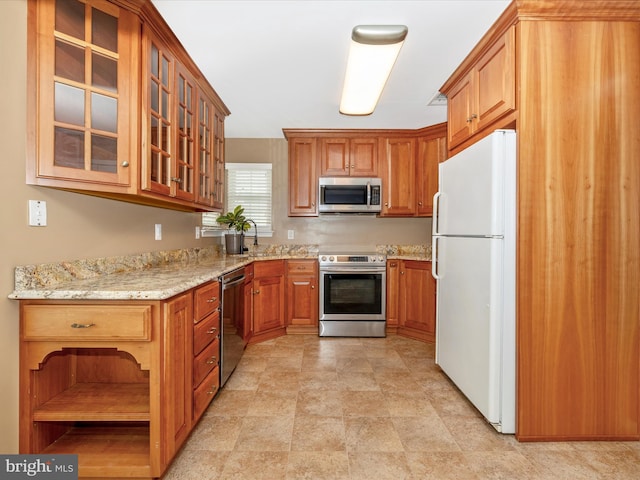 kitchen with light stone counters, stainless steel appliances, and sink