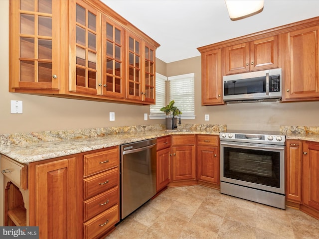 kitchen featuring light stone counters, stainless steel appliances, and sink