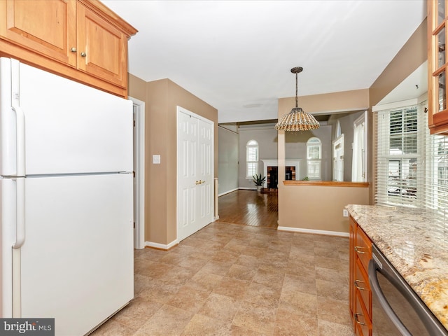 kitchen with pendant lighting, dishwasher, white fridge, light stone counters, and a brick fireplace