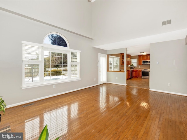 unfurnished living room featuring light hardwood / wood-style floors and a high ceiling