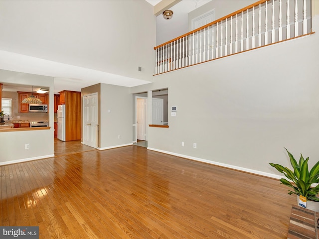 unfurnished living room with a towering ceiling and light hardwood / wood-style flooring