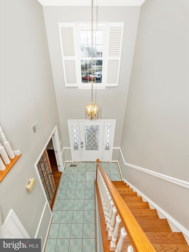 foyer with plenty of natural light, a chandelier, and a high ceiling