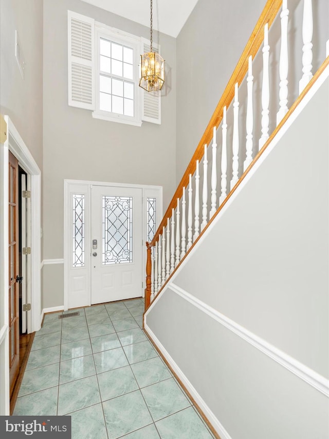 tiled entrance foyer featuring an inviting chandelier and a high ceiling