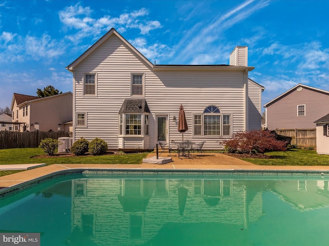 rear view of property with a fenced in pool, a patio, and a yard