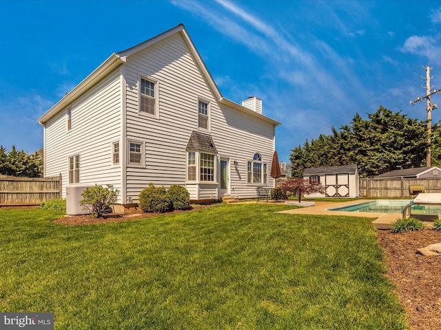 rear view of property with a fenced in pool, a lawn, a patio, and a storage unit