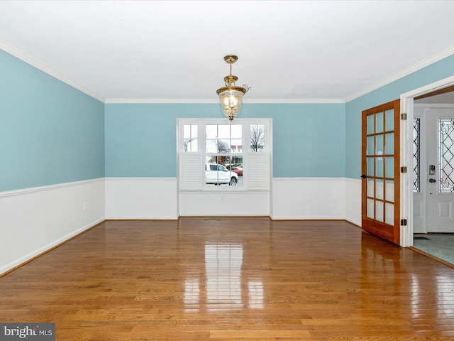 unfurnished dining area featuring wood-type flooring, a notable chandelier, and crown molding