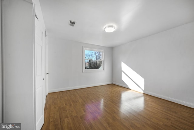 empty room featuring visible vents, baseboards, and wood finished floors