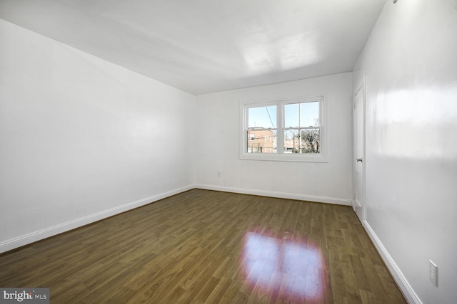 spare room with dark wood-type flooring and baseboards